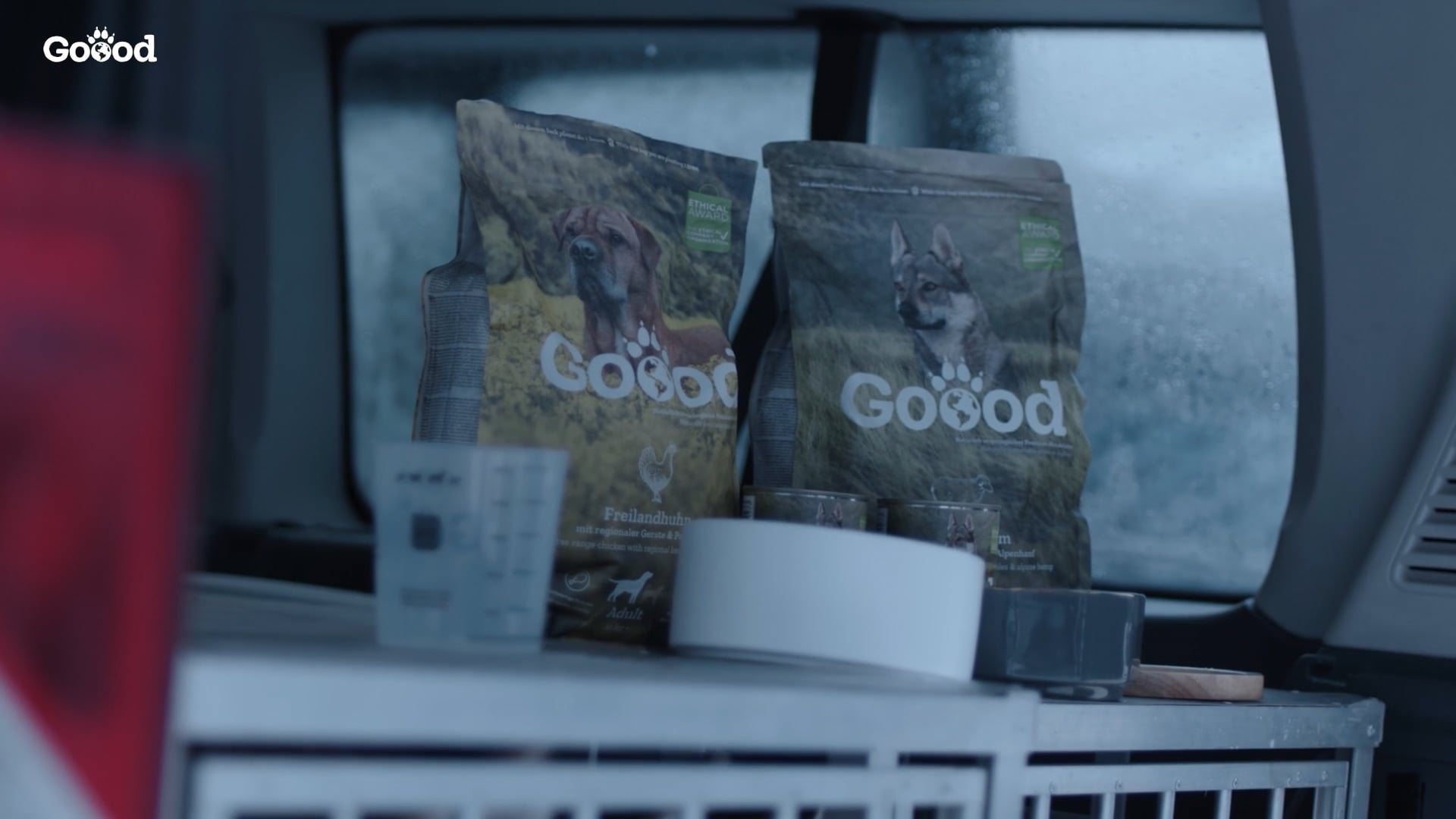 Mehrere Packungen GOOOD Hundefutter mit Futternapf im Innenraum eines Fahrzeugs